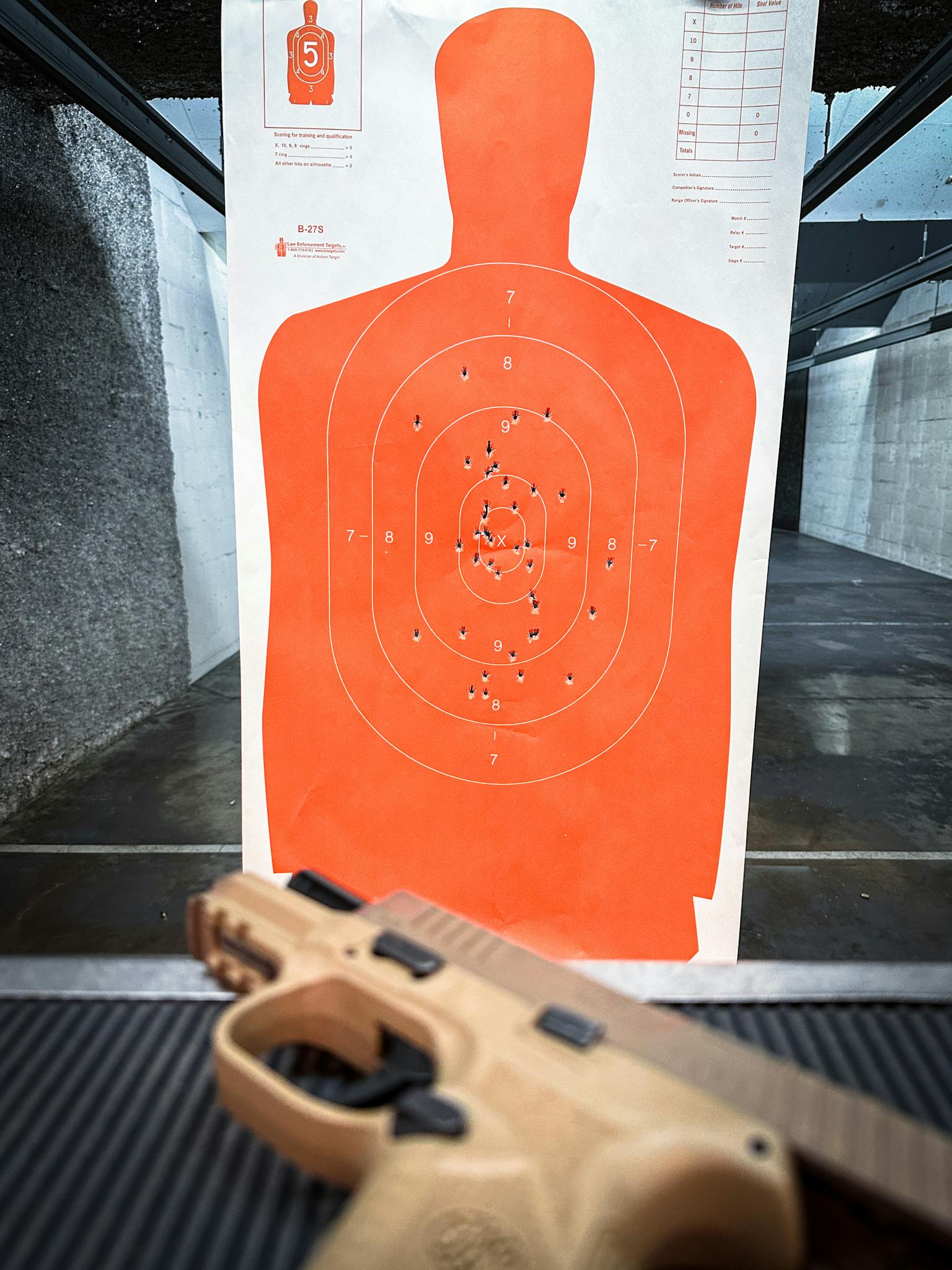 Close-up of a handgun and silhouette target on an indoor shooting range for practice.